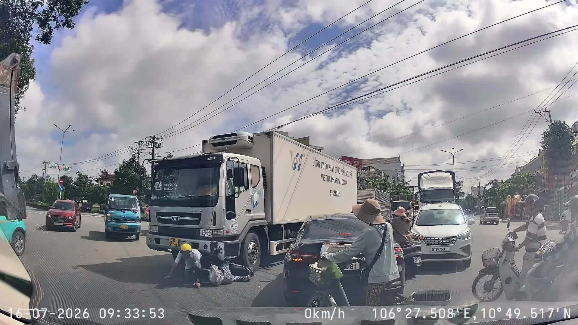 Len qua khe hẹp, hai người đi xe máy bị xe tải đâm ngã